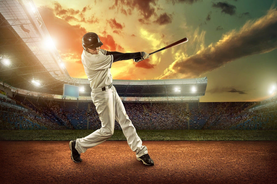 A bedroom features the Baseball Player in Action Wall Mural showing a batter in a stadium at sunset, along with a bed, computer desk, chair, shelves, soccer ball, closet, and sunlight streaming through left-side blinds.