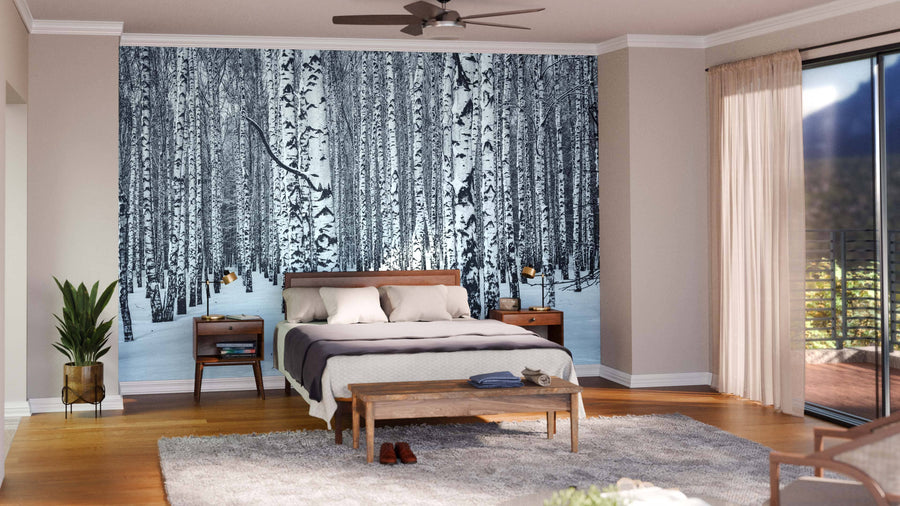 A spacious, modern living and dining area has wood floors, teal chairs, a unique wooden coffee table, and a large Black and White Birch Trees Wall Mural. The dining table seats eight with pendant lights above and an open kitchen in the background.