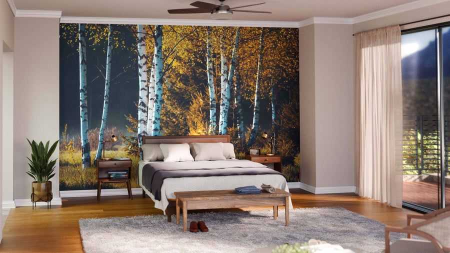 A modern living-dining room features wooden floors, teal and wood chairs, a gray sofa, a large dining table, and the Birch Trees In Autumn Forest Wall Mural dividing the space. Round pendant lights hang above the dining area.