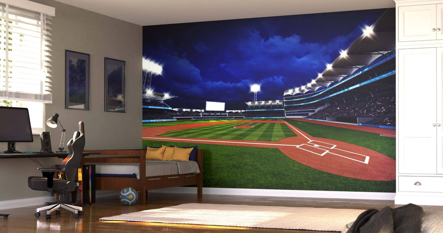 A bedroom showcases the Lit Baseball Stadium Wall Mural. There’s a desk with a chair and computer, a daybed with pillows, a soccer ball on the floor, and sunlight streaming through window blinds.