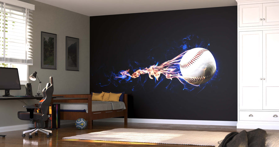 A modern bedroom showcases the Baseball on Fire Wall Mural, depicting a fast-flying baseball with blue and orange flames. The space includes a single bed, desk and chair, computer, soccer ball, and white cabinets illuminated by sunlight.