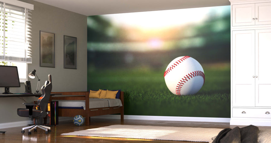 A bedroom features a Baseball on the Grass Wall Mural with a matte canvas texture, yellow pillows on the bed, a desk with computer and chair, soccer ball on the floor, and a white wardrobe by the window.