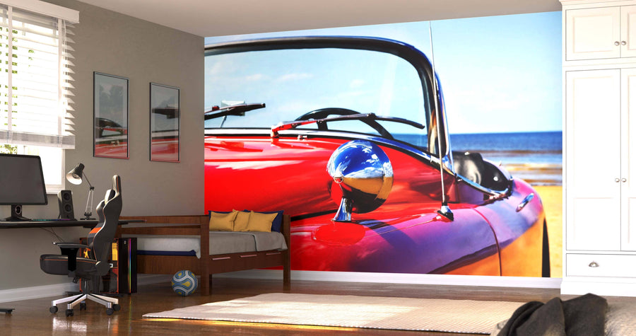 A modern open-plan living and dining area features wood floors, colorful chairs, a dining table, and a striking Classic Red Jaguar Wall Mural by the ocean—creating a vibrant retro focal point in this stylish space.