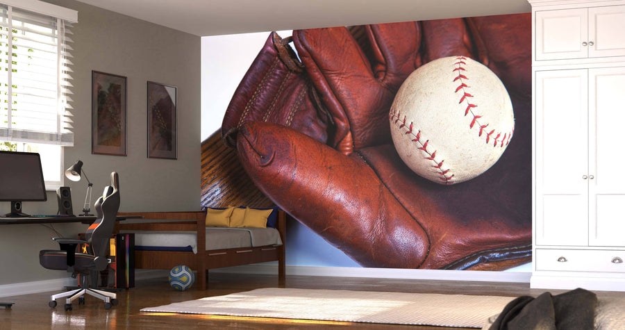 A bright bedroom features the Close Up of Baseball Equipment Wall Mural, showing a baseball in a leather glove. The space also includes a bed with a yellow pillow, sports posters, a soccer ball, and sunlight through window blinds.