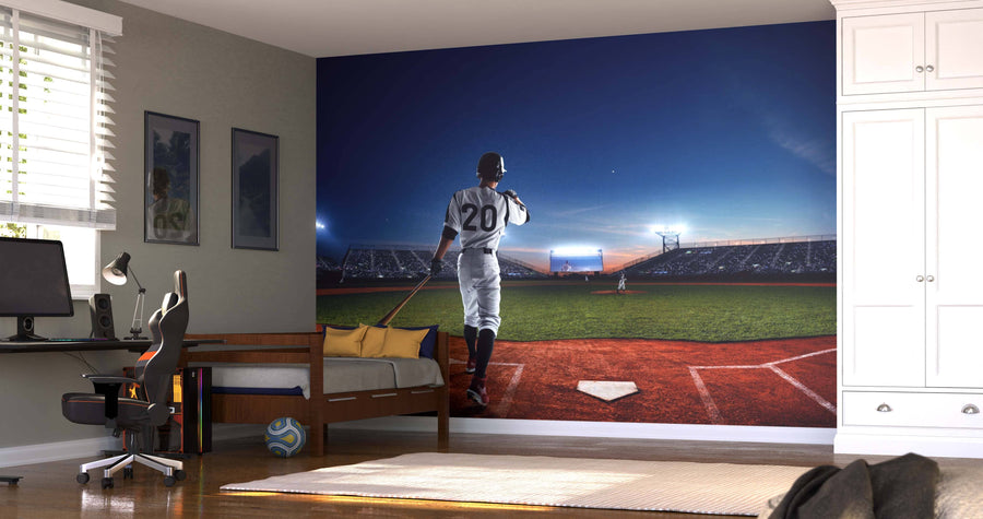 A bedroom with a desk, chair, and bed features the Home Run Wall Mural, showing a baseball player wearing number 20 at home plate in a brightly lit stadium at dusk. A soccer ball is on the floor near the bed.