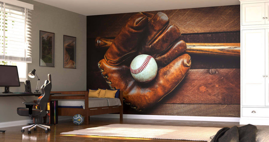 A modern bedroom features a Vintage Baseball Gear Wall Mural with a glove, bat, and ball behind a desk and bed. Sunlight filters through blinds, a soccer ball sits near the bed, and white cabinets are seen on the right.