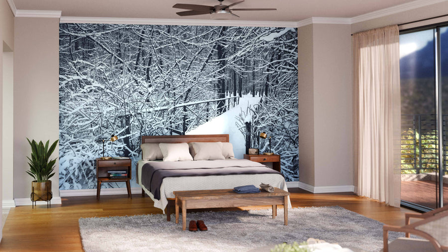 A modern living-dining space features wood floors, green armchairs, a sofa, and hanging lights. The back wall displays the "Bridge in Forest on Winter Day Wall Mural," bringing a scenic, wintry look to the open room.