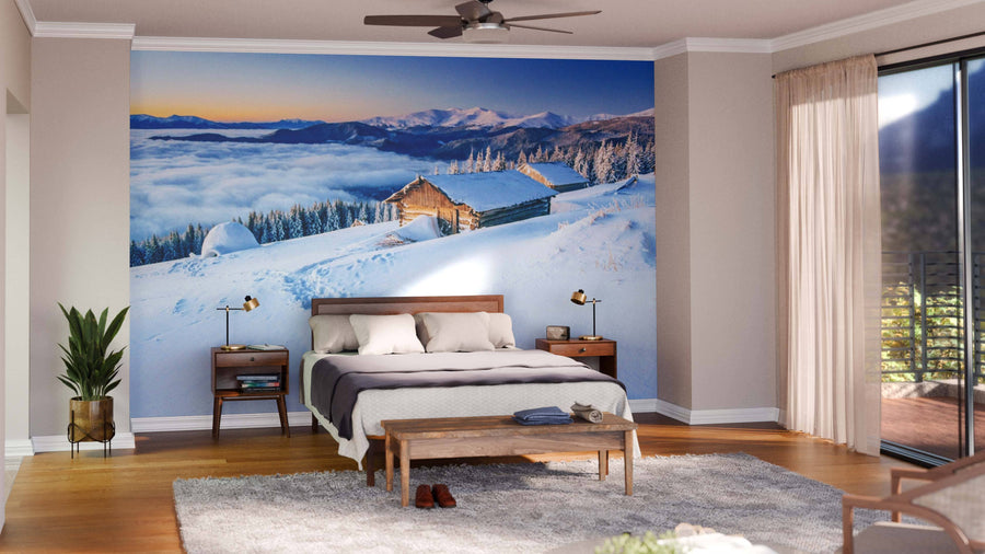 A modern living-dining room features wooden floors, stylish furniture, and the "Chalets in the Mountains Wall Mural," displaying a snowy mountain cabin at sunrise. This vibrant mural creates a cozy atmosphere in the contemporary space.