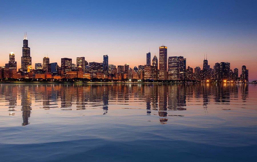A modern conference room features a long wooden table, ten black chairs, floor-to-ceiling windows, and the "Chicago Skyline at Sunset From the Observatory Wall Mural." Glass walls reveal an adjacent office space with a similar design.