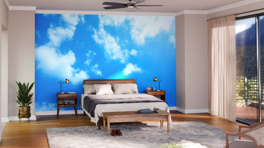 A modern living and dining room with wood floors, green chairs, a Clear Sky Wall Mural on the main wall, a dining table with globe lights, and a kitchen area in the background.