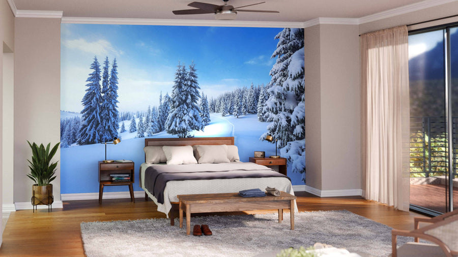 A modern open-plan living and dining room features wood floors, mid-century furniture, and a large Covered Winter Forest Wall Mural. Pendant lights hang over a dark dining table, with houseplants adding greenery.