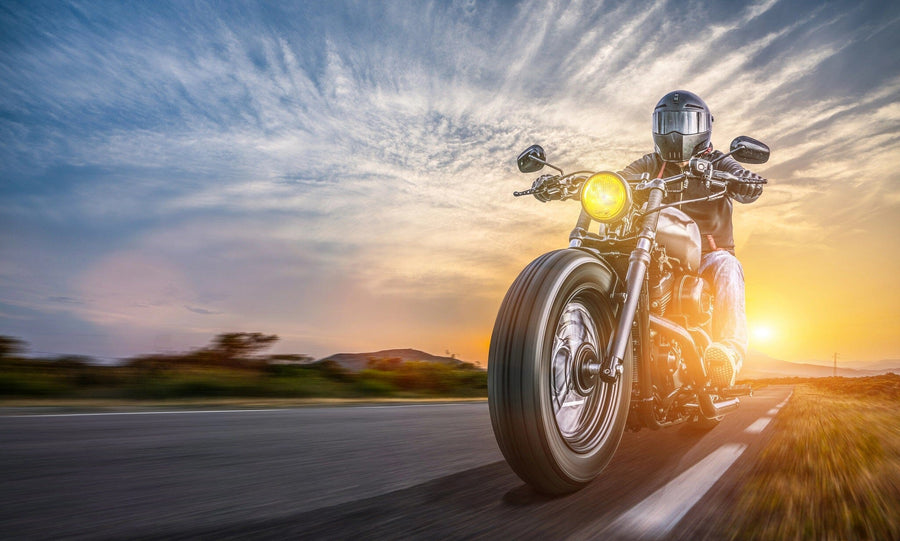 A modern garage with sleek black cabinets, organized tools, and a vintage motorcycle features the "Cruising into Sunset Wall Mural" on the back wall, adding dynamic energy to the clean, well-lit space.