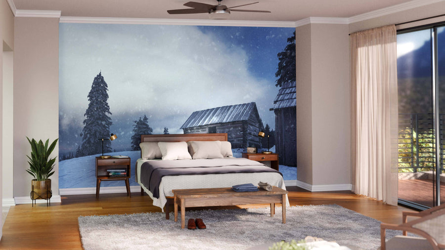 A modern open-concept living and dining area with wood floors and furniture features the Empty House on the Mountain Wall Mural. Blue armchairs, a gray sofa, round rug, and a dining table with hanging lights complete the cozy decor.