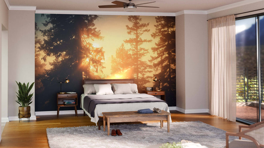 A bright bedroom features a bed, wooden nightstands, bench, and plant. Behind the bed, the Foggy Scandinavian Mount Wall Mural adds charm, while sunlight pours in through glass doors to illuminate the cozy, well-organized space.