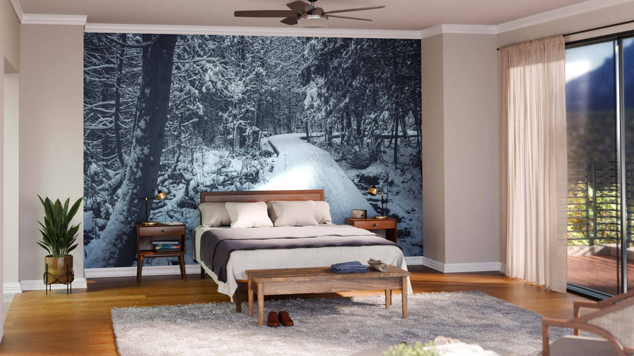 A modern open-plan living and dining room with wooden floors, teal armchairs, and a large Forest Landscape With Snow Wall Mural. The dining area has a dark table, wooden chairs, and globe pendant lights, with the kitchen visible in the background.
