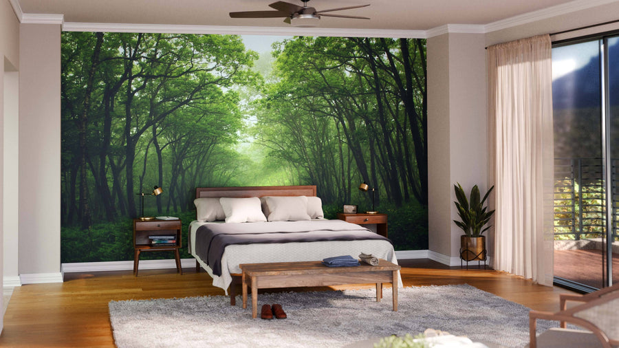 A modern living and dining room with wood furniture and green chairs features the Forest Mystic Way Wall Mural, bringing a lush outdoor feel. Pendant lights above the table and rugs on the wooden floor make the space bright and inviting.