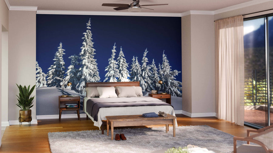 A modern living-dining room features wood floors, teal armchairs, a large dining table with six wooden chairs, and a Fragile Tree Covered in Frost Wall Mural. Warm lighting and contemporary decor create a cozy, stylish atmosphere.