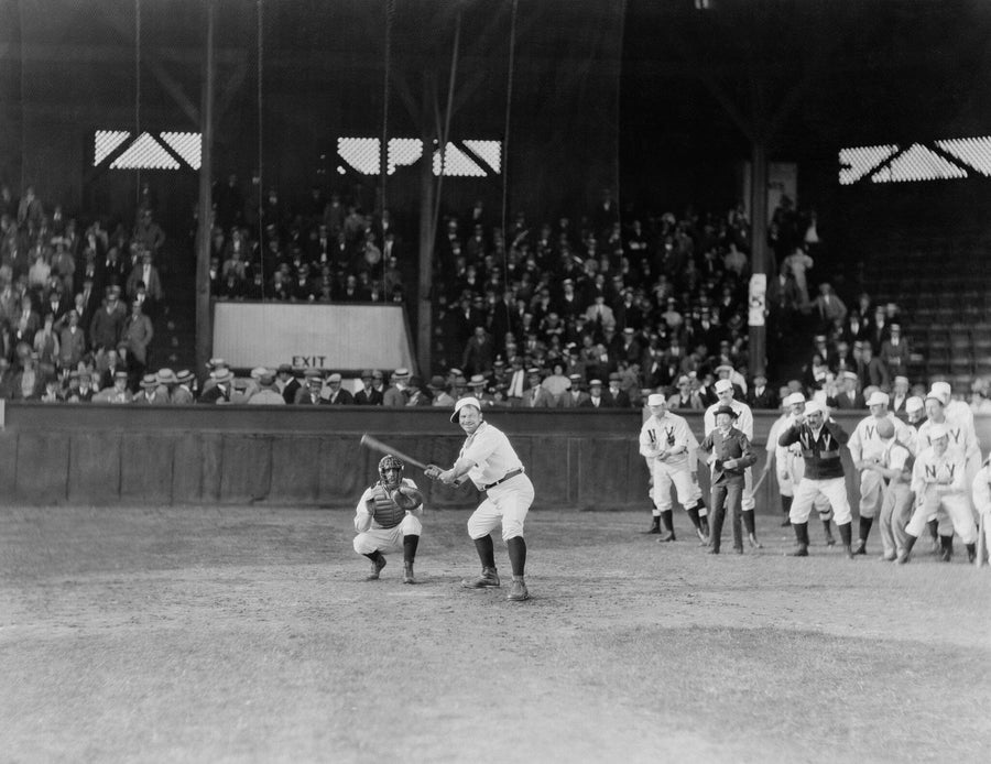 A bedroom with a desk, computer, and bed features the Game On The Line Wall Mural—a large black-and-white print of an old-time baseball game. Modern furnishings, light wood flooring, and removable wallpaper make for easy style updates.