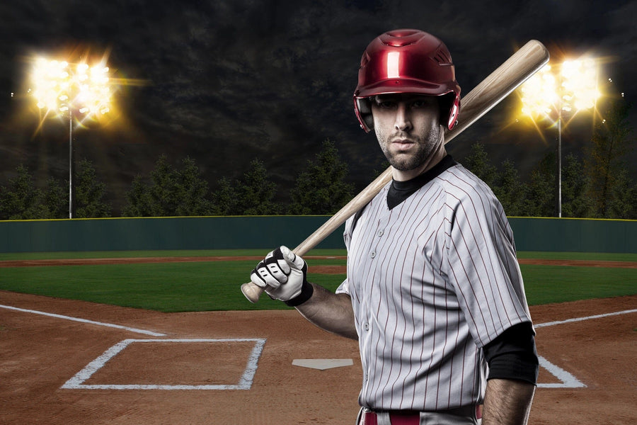 A bedroom includes a workspace, bed, and the Game Time Wall Mural depicting a serious baseball player in a red helmet and striped uniform on a lit night field. Neutral walls, modern furniture, and sports decor complete the look.