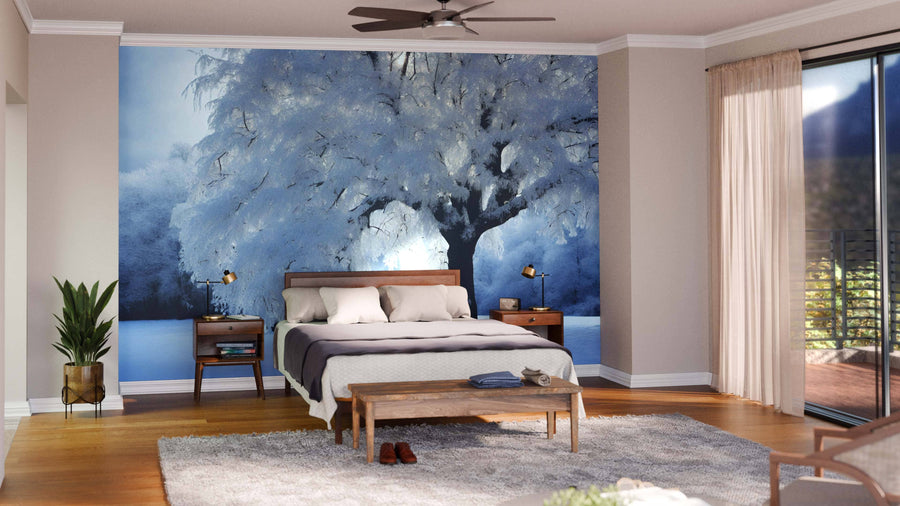 A modern living-dining room boasts wooden floors, dark wood furniture, teal chairs, a patterned rug, and a Heavy Snow-Covered Tree Wall Mural with soft lighting and minimalistic decor. The kitchen is visible in the background.