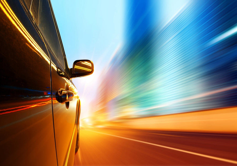 A modern bedroom with a desk, bed, and wardrobe. The main wall showcases the High-Speed Car at Night Wall Mural, featuring vibrant light trails and motion blur for a dynamic effect. Sunlight streams through a window with white blinds.