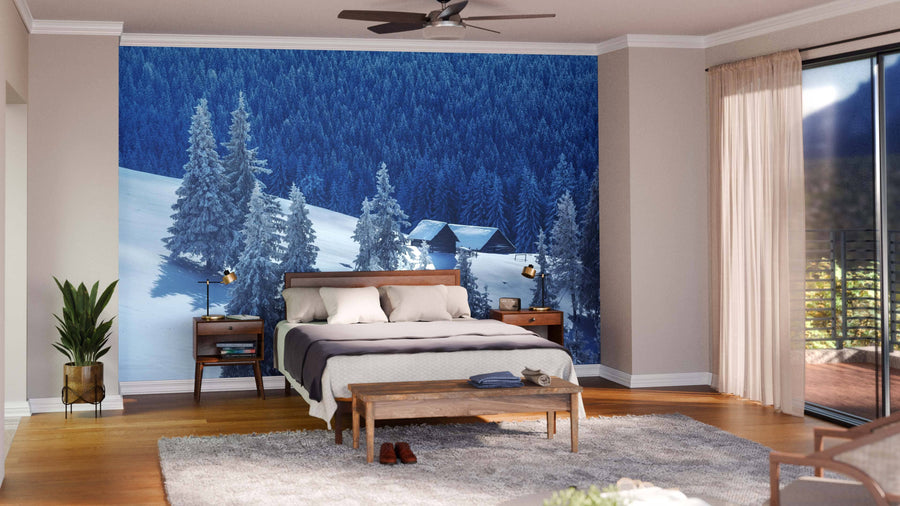 A modern living-dining room features wood floors, dark wood furniture, teal chairs, and the House on the Hill with Snow Wall Mural. Pendant lights, a patterned rug, and a glimpse of the kitchen complete this stylish space.