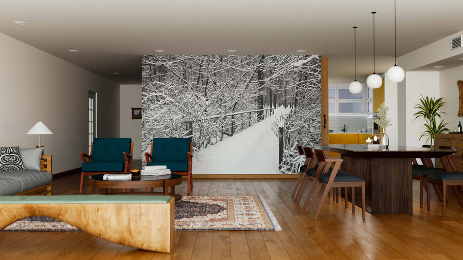 A modern living-dining space features wood floors, green armchairs, a sofa, and hanging lights. The back wall displays the "Bridge in Forest on Winter Day Wall Mural," bringing a scenic, wintry look to the open room.