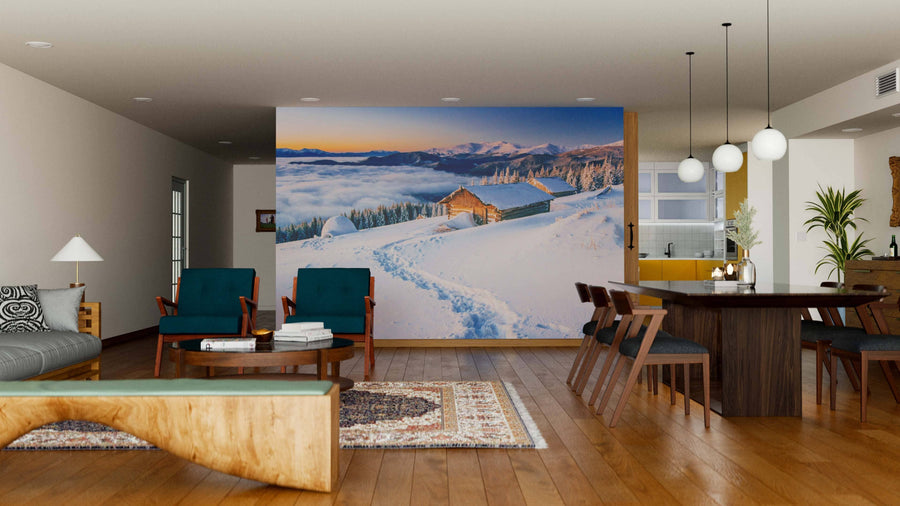 A modern living-dining room features wooden floors, stylish furniture, and the "Chalets in the Mountains Wall Mural," displaying a snowy mountain cabin at sunrise. This vibrant mural creates a cozy atmosphere in the contemporary space.