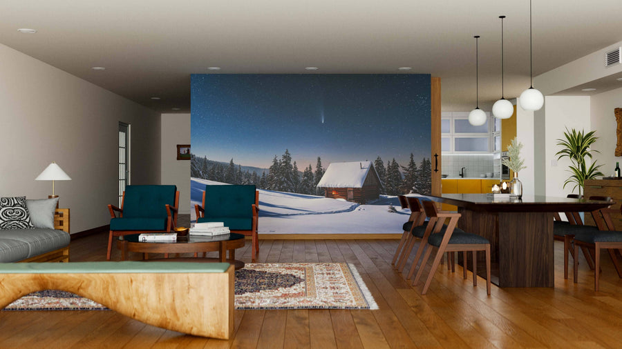 A modern living and dining room with wooden floors, furniture, and indoor plants features the Fantastic Winter Landscape Wall Mural showing a snowy cabin at night, plus a dining table, lounge chairs, sofa, rugs, and lamps.