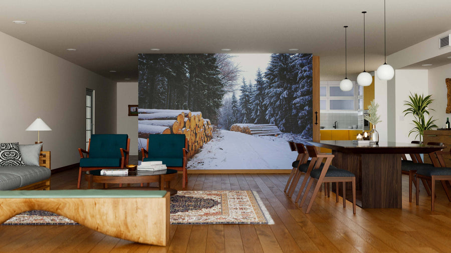 A modern living-dining space with wooden floors, blue armchairs, a wooden table, and the Pine Logs Under Snow Wall Mural. Soft lighting, a patterned rug, and minimalist furniture create a cozy, natural ambiance.