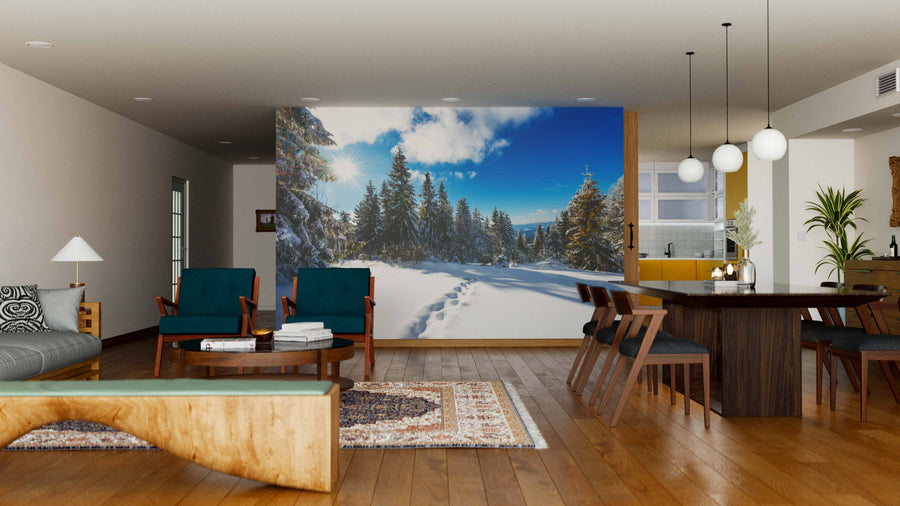 A modern living-dining room with wood floors features cozy seating, a dining table, pendant lights, and neutral decor. A Road in Snow-Covered Forest Wall Mural covers one wall, adding natural beauty to the space.