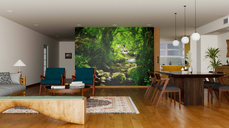 A modern living-dining room with wooden floors, teal armchairs, and a dining set features the Stream in Green Forest Wall Mural on the back wall, creating a stunning nature-inspired focal point for the space.