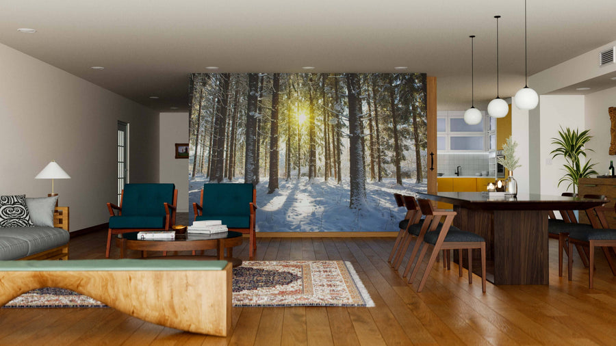 A modern open-plan living and dining space features wooden furniture, green chairs, rugs, pendant lights, and a Sunlight in the Winter Wall Mural—a peel and stick wall mural of a snowy forest—bringing a warm, nature-inspired feel.