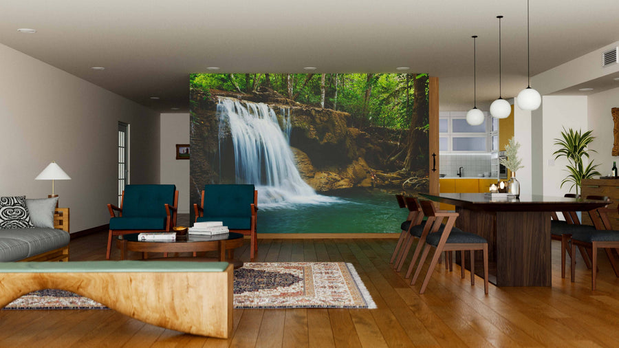 A modern living-dining room features wooden floors, stylish furniture, and the "Waterfall in a National Park Wall Mural," which divides the spaces and creates a serene, natural focal point in the contemporary open-plan interior.