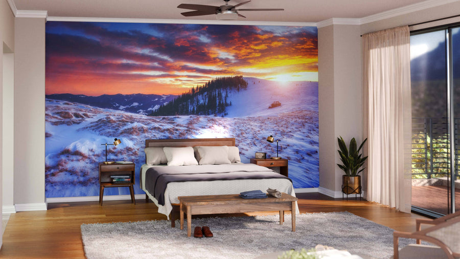 A modern living-dining area with wooden floors and mid-century furniture features the Majestic Winter Trees Glowing Wall Mural depicting snowy mountains at sunset. Spherical lights above the dining table add warmth to this stylish space.