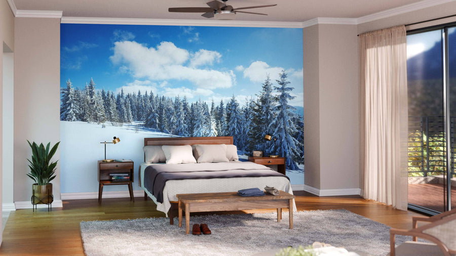 A modern open-plan living and dining area with wooden floors, teal and wood chairs, and a sofa is brightened by the Mesmerizing Picturesque Landscape Wall Mural, depicting a snowy pine forest under a blue sky.