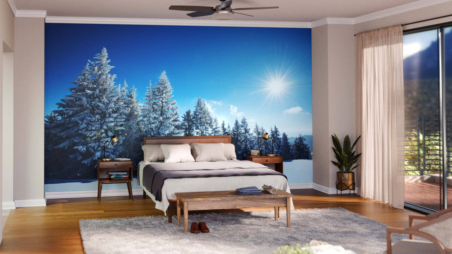 A modern living and dining room features wood furniture, blue-green accents, a patterned rug, and the Mesmerizing Winter Landscape Wall Mural, bringing a snowy forest scene indoors for a cozy wintery ambiance.