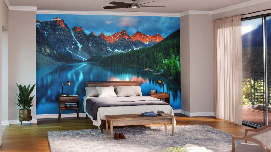 A modern open-plan living and dining area with wood flooring, stylish furniture, and a Moraine Lake Sunrise Banff Canada Wall Mural featuring sunset peaks reflected in the lake, creating a striking focal point in the space.