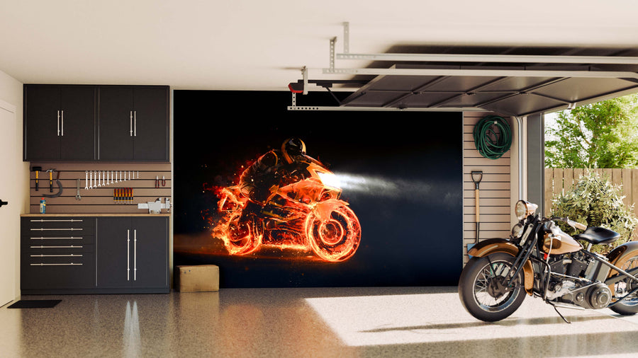 A tidy garage with dark cabinets and tools on the left, a motorcycle parked on the right, and a Blazing Bike Wall Mural on the back wall featuring a glowing motorcycle and rider made of fiery orange light streaks on a black background.