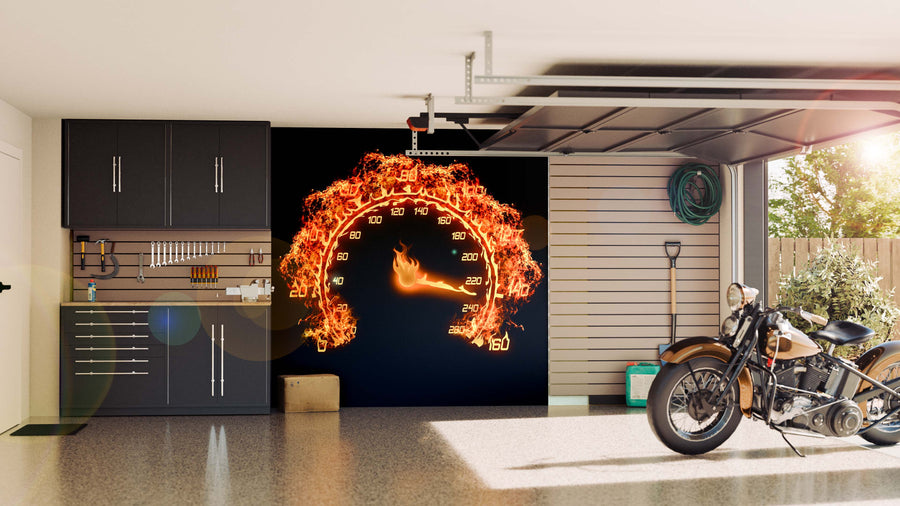A clean garage with black cabinets, organized tools, and a motorcycle. The back wall showcases the Burning Speedometer Wall Mural, featuring fiery flames over numbers. Sunlight pours in from the half-open garage door.