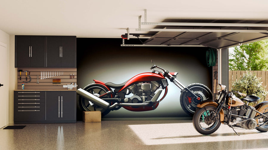 A clean garage with cabinets and tools on the left, a Concept Motorcycle Wall Mural of a red bike on the wall, and a real custom motorcycle parked on the right. Sunlight from the open door illuminates green plants outside.