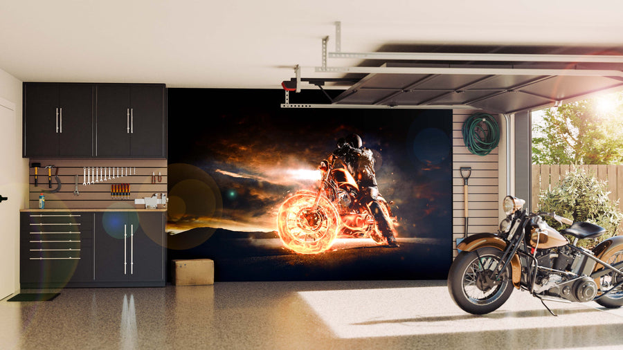 A modern garage features black cabinets and organized tools on the left. A dramatic Motorcycle with Flames Wall Mural is displayed, with a vintage-style motorcycle parked nearby, sunlight streaming in, and greenery outside.