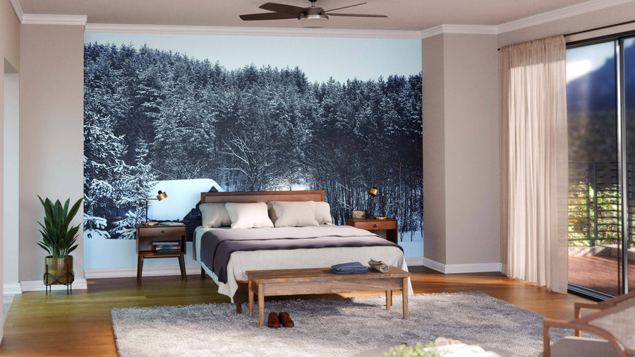 A modern living-dining room with wooden floors, teal and wood furniture, and the Old Log Cabin in Winter Wall Mural. Pendant lights, cozy rugs, a dining table, and plants create a warm, inviting atmosphere.