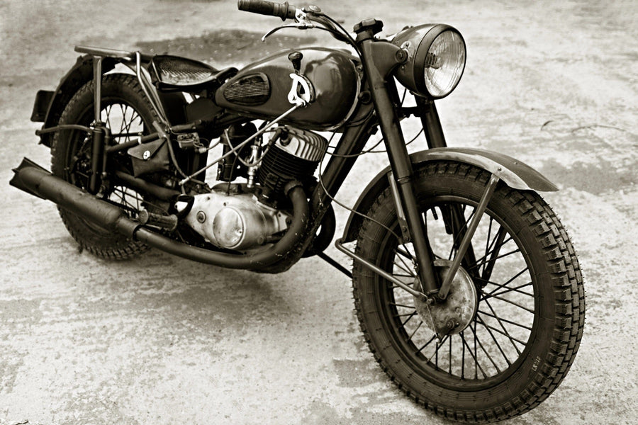 A modern garage with sleek black cabinets, organized tools, and an Old Motorcycle Wall Mural. Sunlight highlights a classic bike and a green hose by the window that overlooks trees.