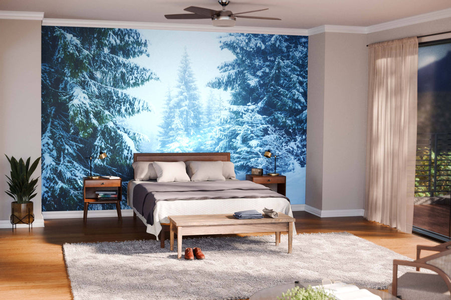 A modern living and dining area with wooden floors, teal chairs, and the "Pine Trees Covered by Snow Wall Mural." A patterned rug, round coffee table, contemporary dining table, and white globe lights complete this cozy space.