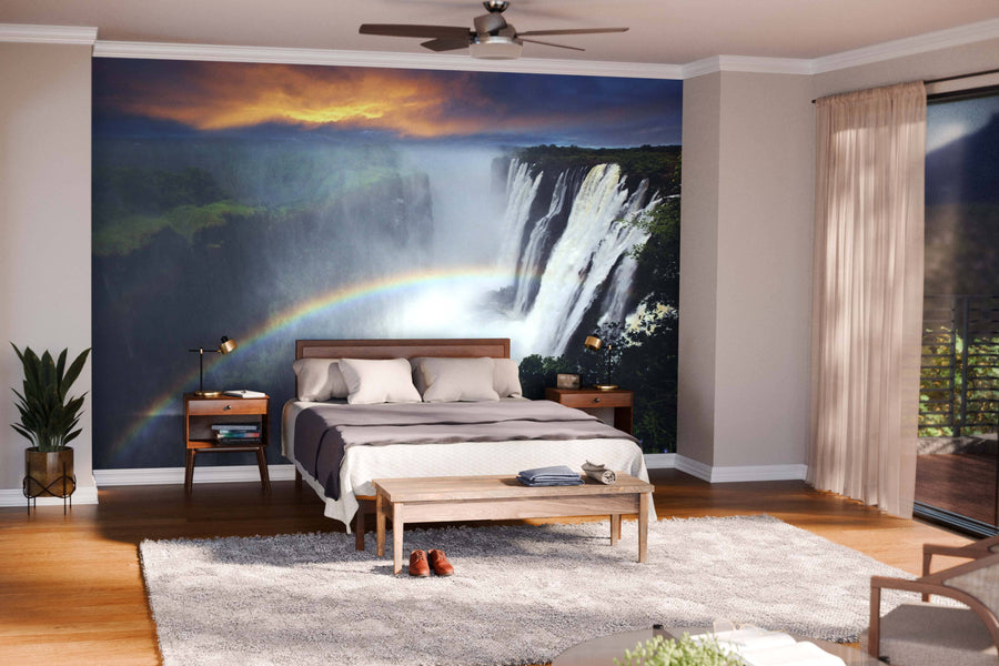 A modern open-plan living and dining room with wooden floors and mid-century furniture features the Rainbow at Waterfalls Wall Mural, adding a vivid waterfall with a rainbow as a striking focal point to the sleek, contemporary decor.