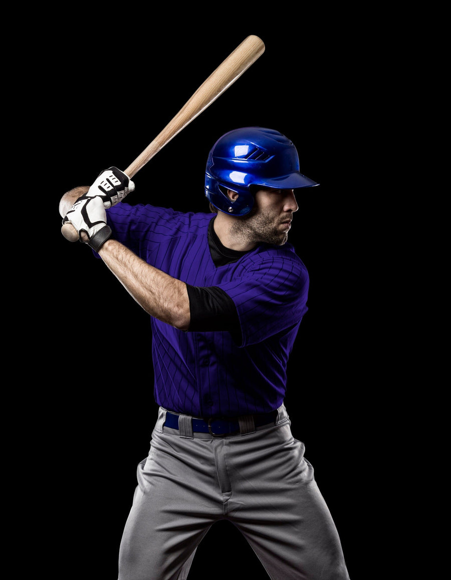 A modern bedroom features the Ready to Hit Wall Mural, showcasing a baseball player in a batting stance behind the bed. Nearby are a desk with a computer and lamp, white cabinets, and sunlight pouring in through the window.