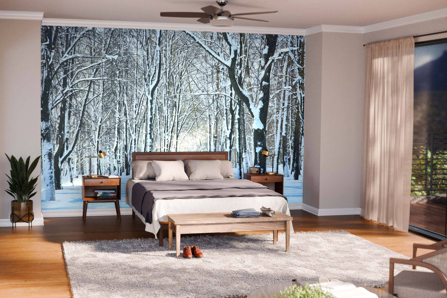 A modern living-dining room with wooden floors, teal chairs, and a large table features the Snow on Trees in April Wall Mural, a peel and stick mural that brings a stylish wintry forest scene indoors with ease.
