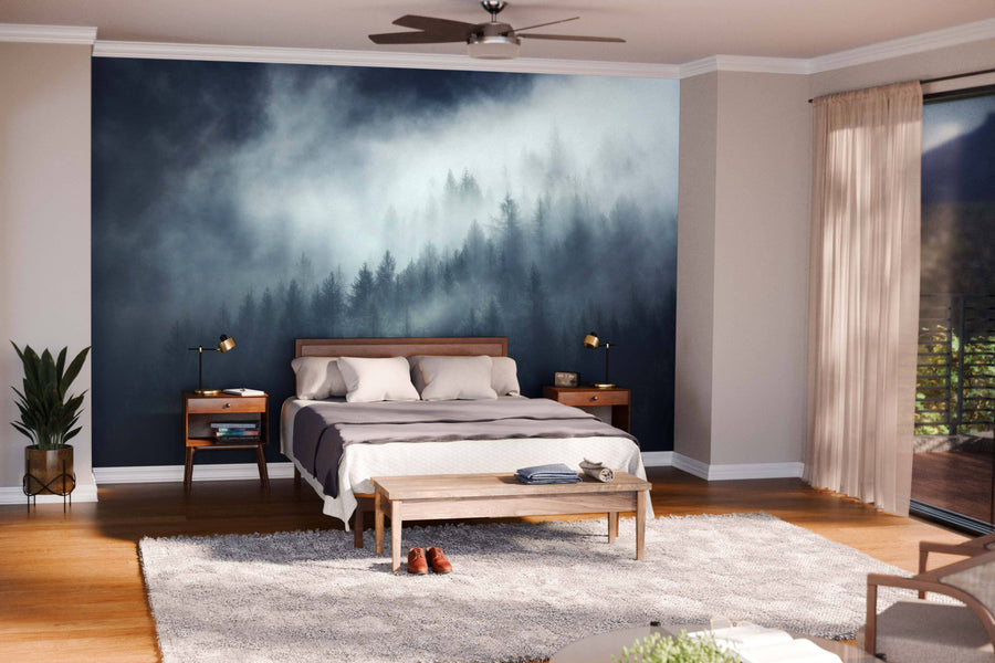 A modern open-plan living and dining area with wooden floors, teal chairs, and a dining table features the South Tyrol Misty Forest Wall Mural. Pendant lights hang overhead, and the kitchen is visible in the background.