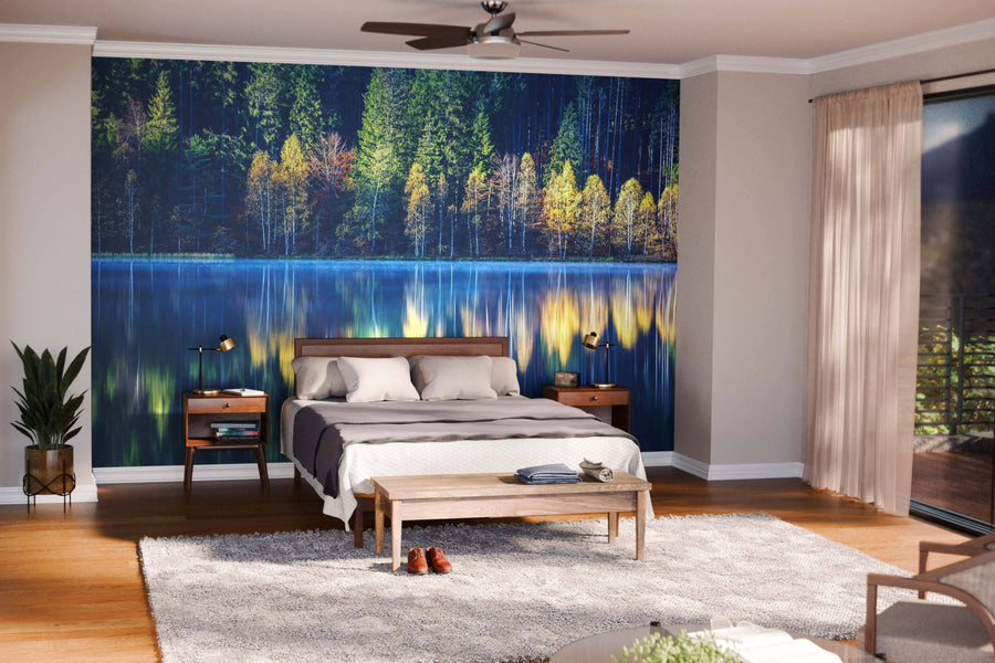 A modern open-plan living and dining room features wooden floors, teal armchairs, a wood bench, dark dining chairs, globe pendant lights, and the stunning Still Lake in Autumn Wall Mural.
